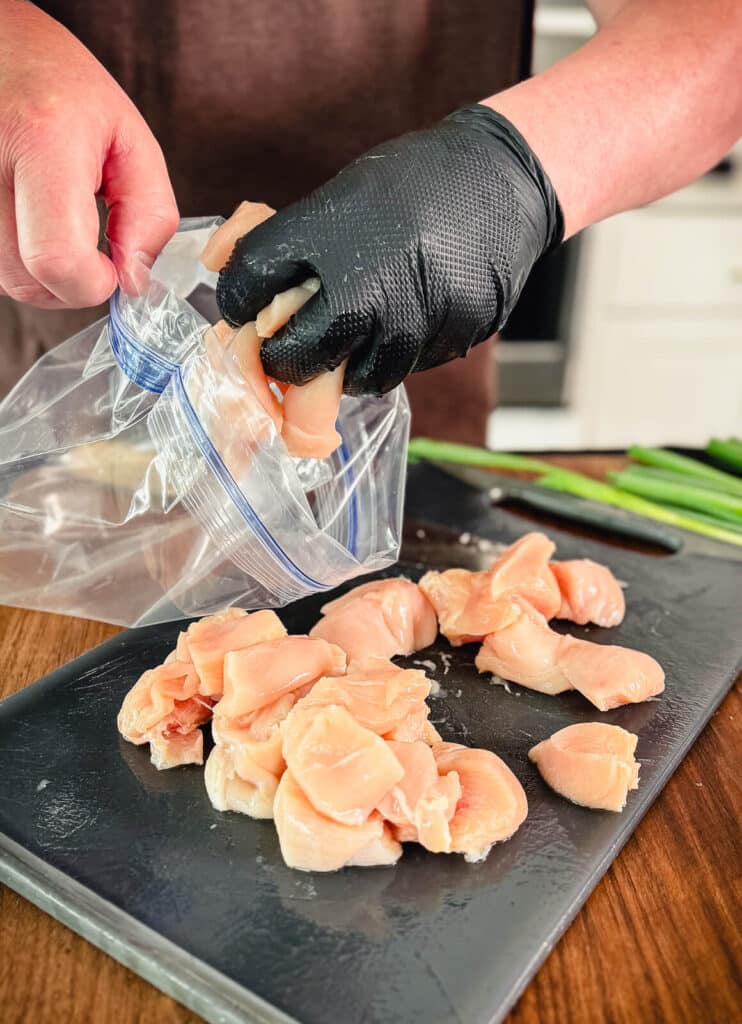 chicken breast cubes being added to a plastic bag
