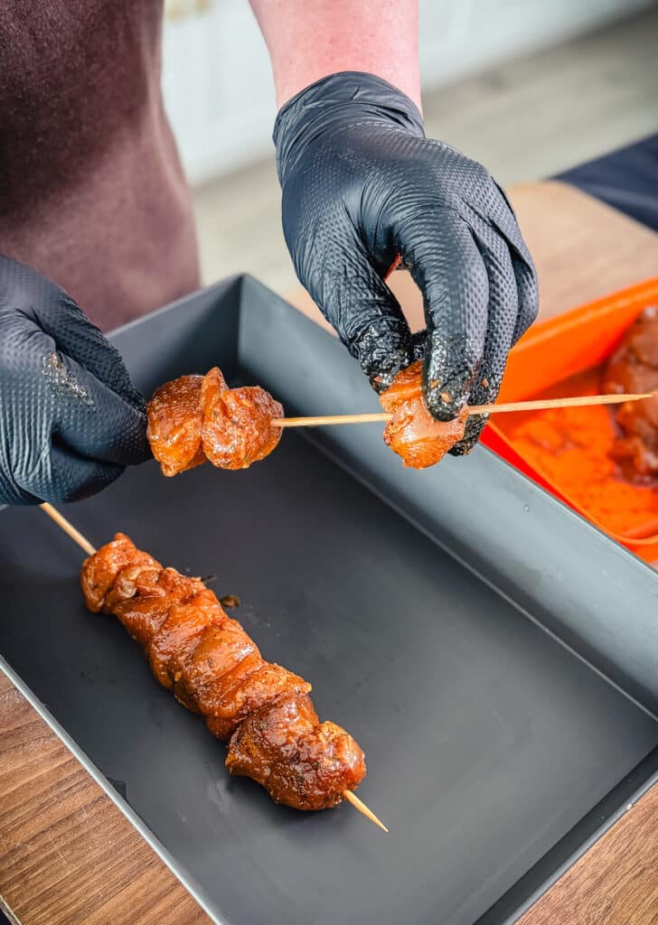 piece of chicken breast being placed onto a skewer