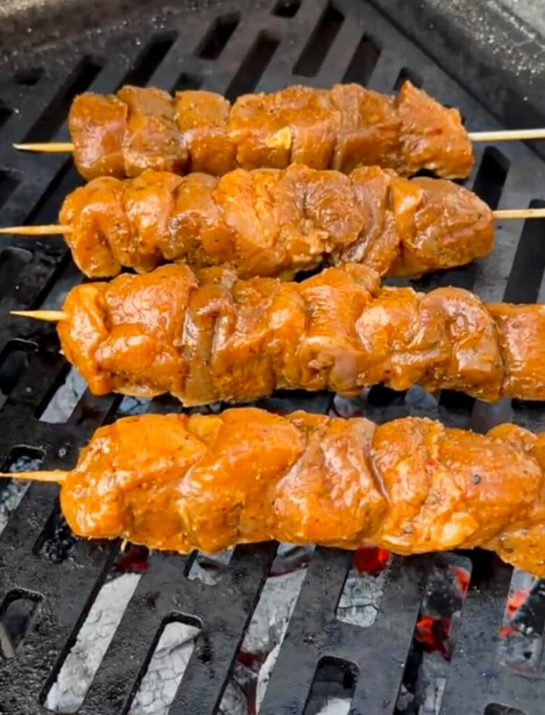 uncooked Peruvian chicken skewer being placed on a grill