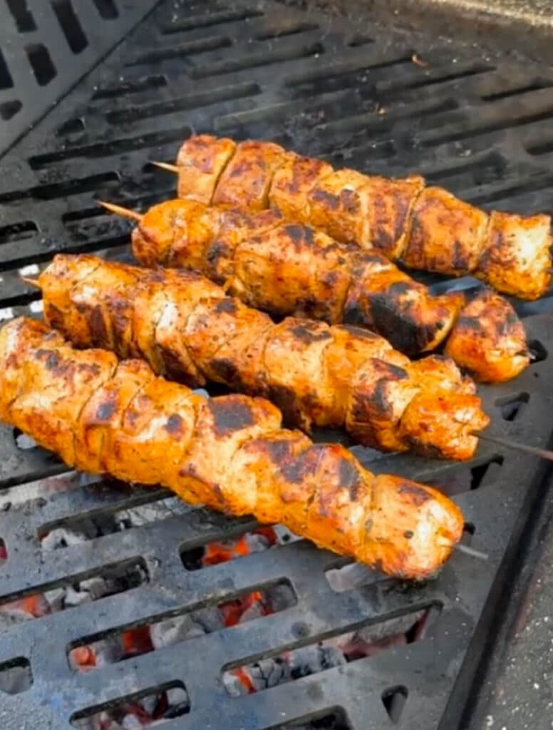 charred Peruvian chicken breast skewer on a grill over hot coals