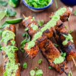 Peruvian chicken breast skewers on a board with aji verde sauce