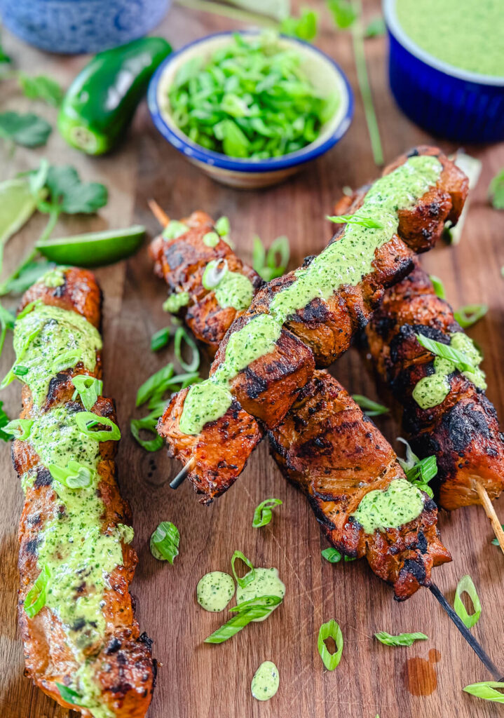 Peruvian chicken breast skewers on a board with aji verde sauce