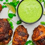 bowl of aji verde sauce on a platter with chicken drumsticks