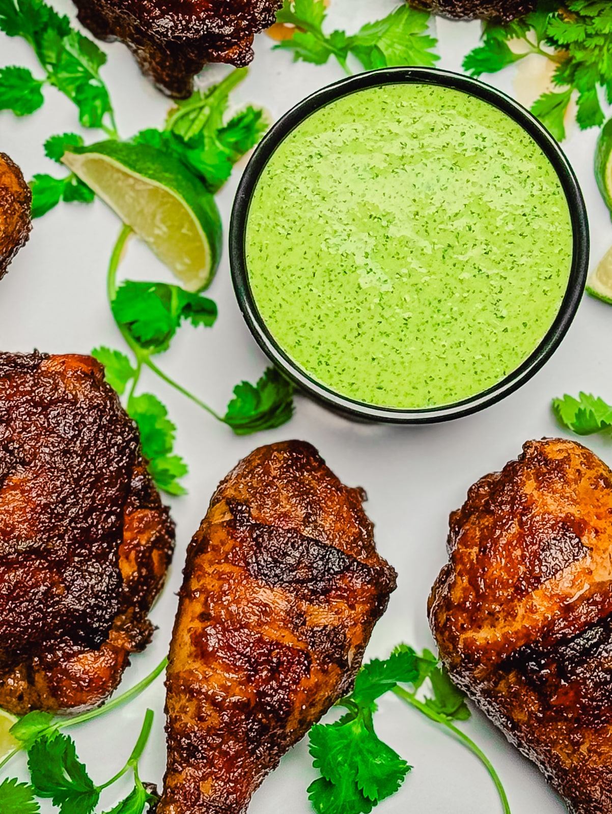 bowl of aji verde sauce on a platter with chicken drumsticks