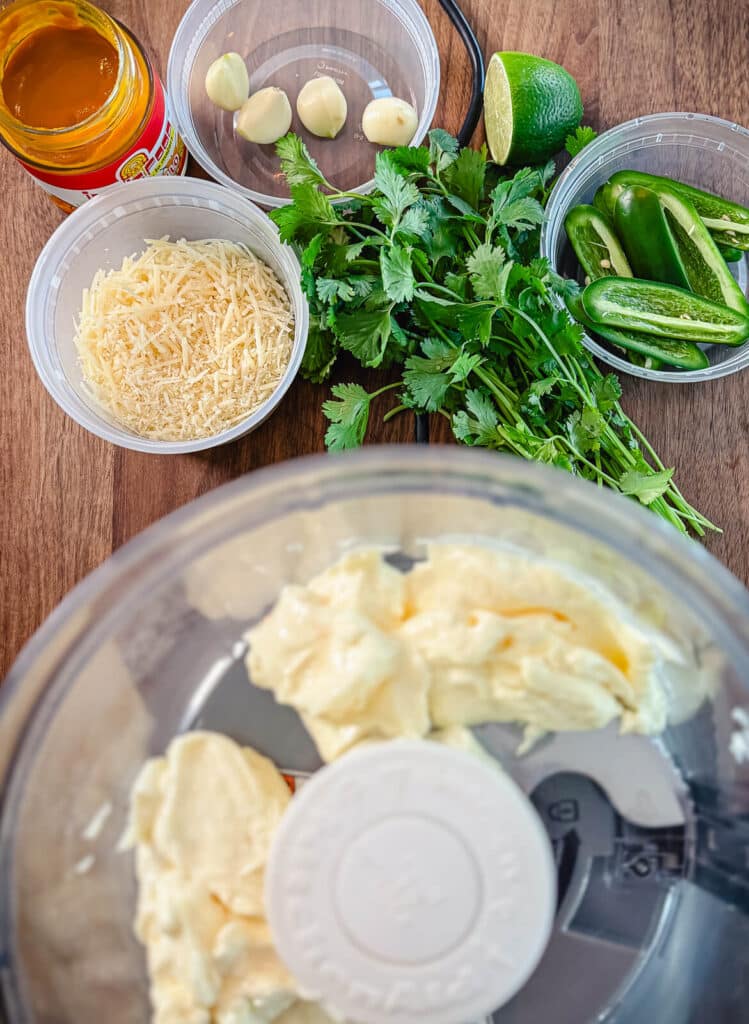 ingredients for aji verde in containers near a food processor