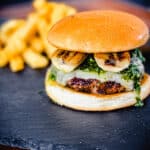 Columbain burger with grilled bananas on a black slate tile with french fries