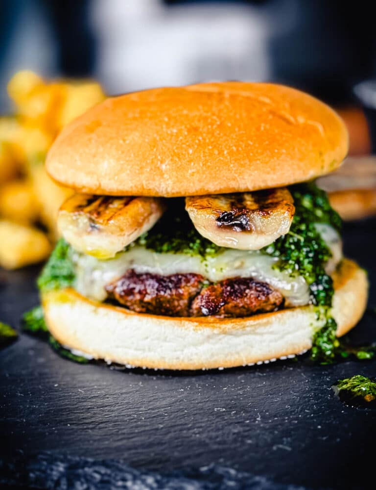 columbian burger with grilled bananas on a black cutting board