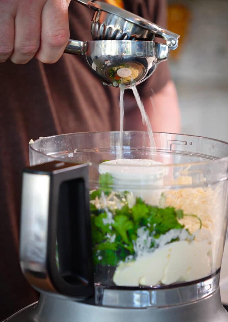 lime juice being squeezed into a food processor