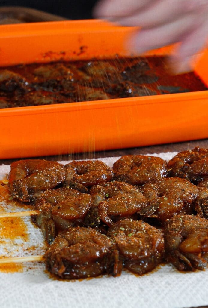 peruvian spice blend being sprinkled onto shrimp skewers