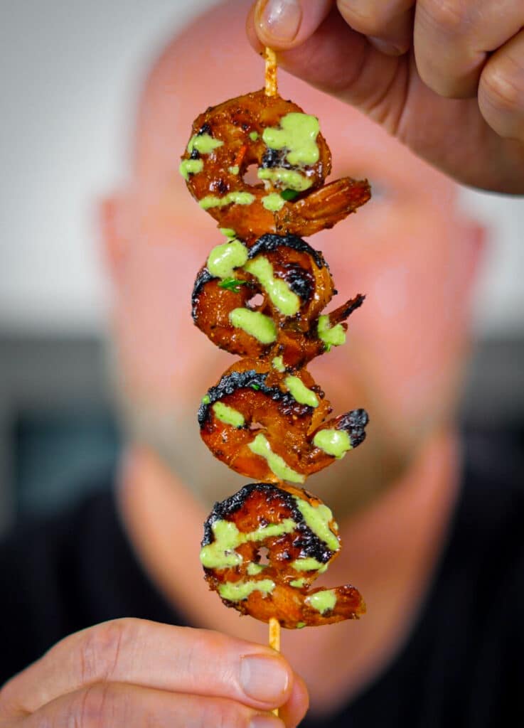 shrimp skewer with aji verde sauce being held up in front of face