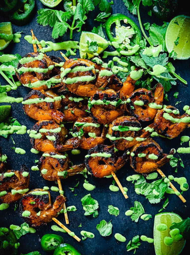 overhead shot of peruvian shrimp skewers on a black platter