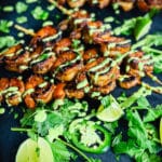 peruvian shrimp skewers on a black platter with jalapenos