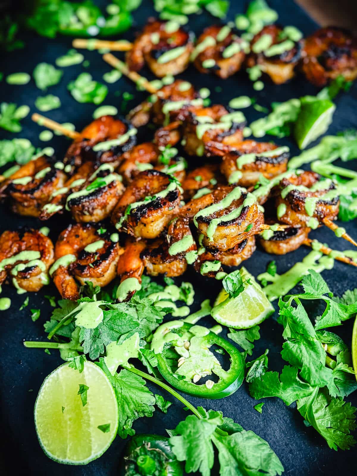 peruvian shrimp skewers on a black platter with jalapenos