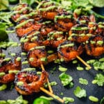 platter of peruvian shrimp skewers with cilantro, aji verde, and limes