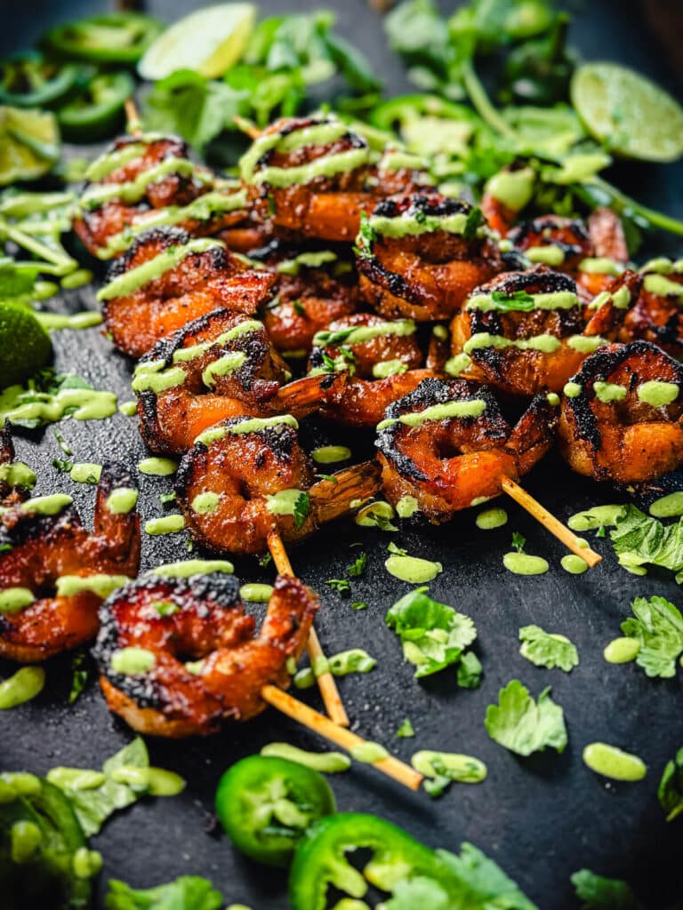 platter of peruvian shrimp skewers with cilantro, aji verde, and limes