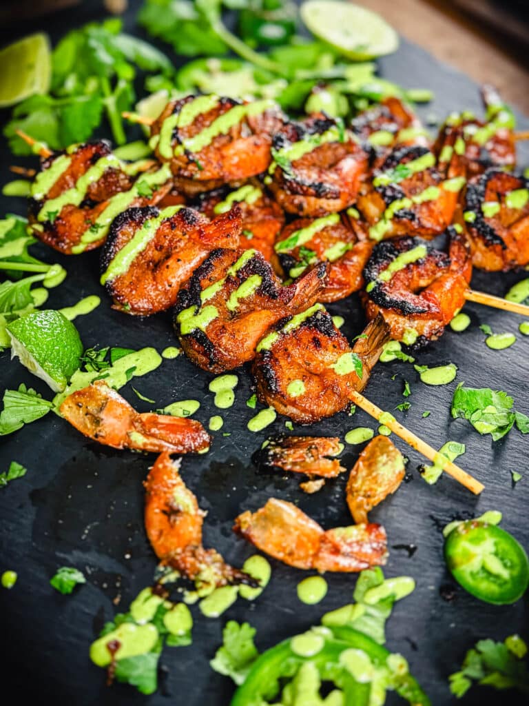 shrimp skewers on a platter with some shrimp tails in the foreground