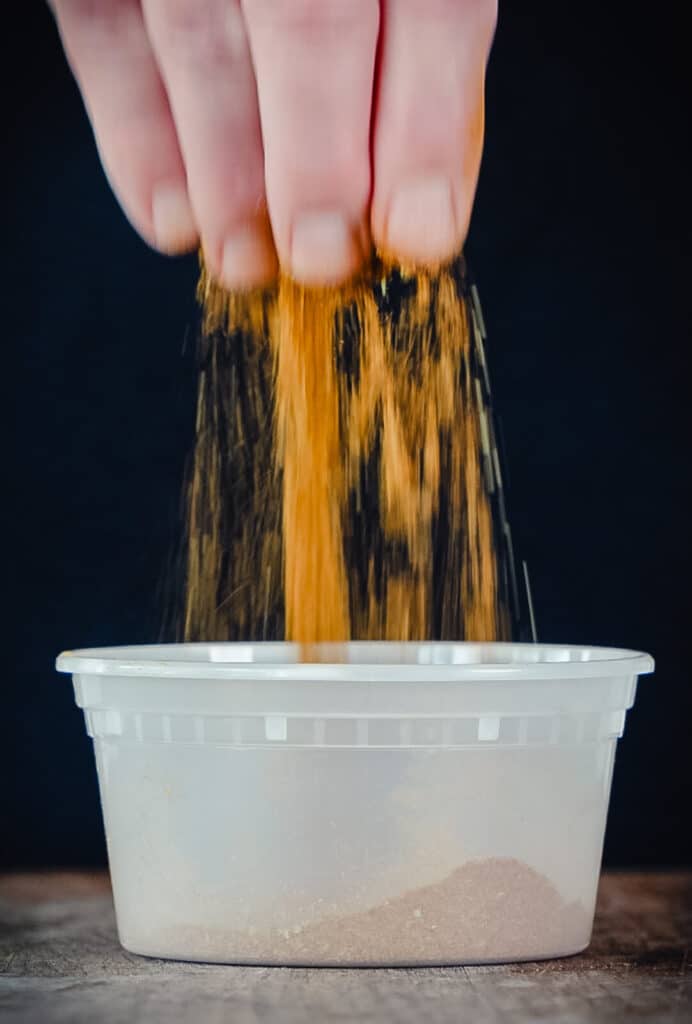 spice blend being sifted through fingers over a bowl