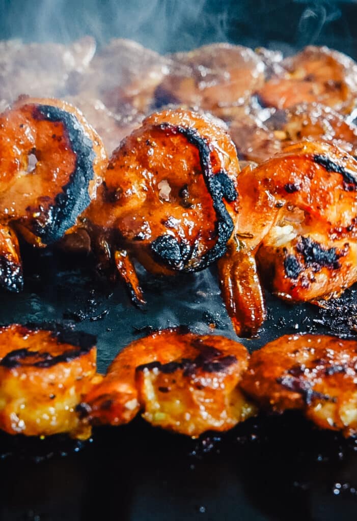 peruvian shrimp skewer being flipped on a griddle surface as it sears