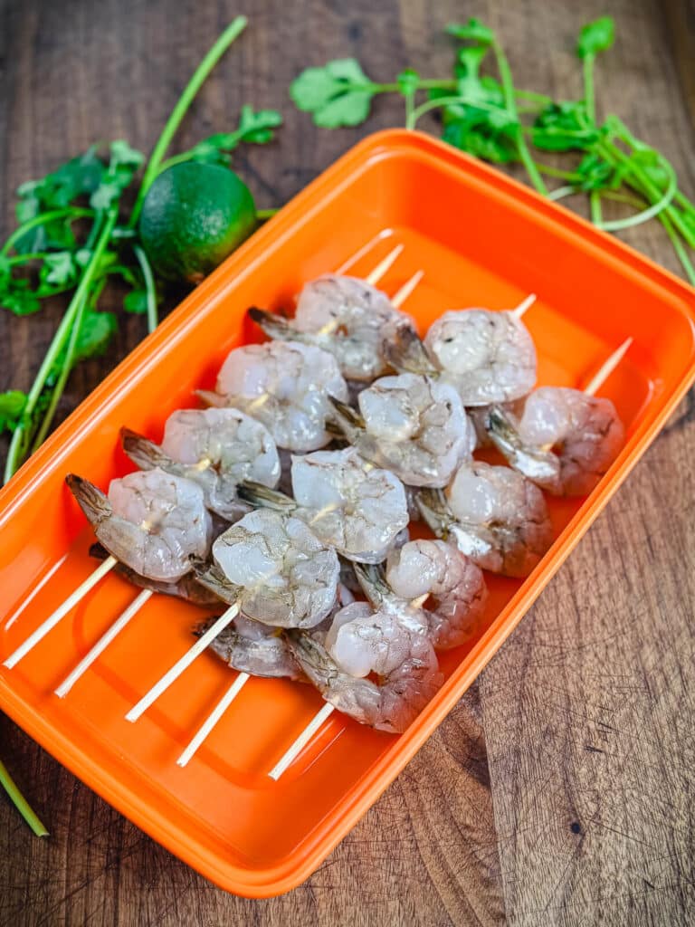 shrimp on wooden skewers in a plastic container