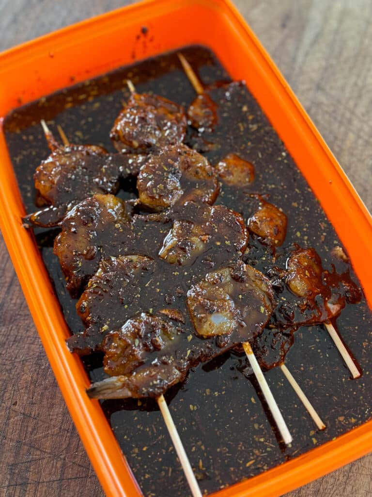 shrimp covered in marinade in a plastic container