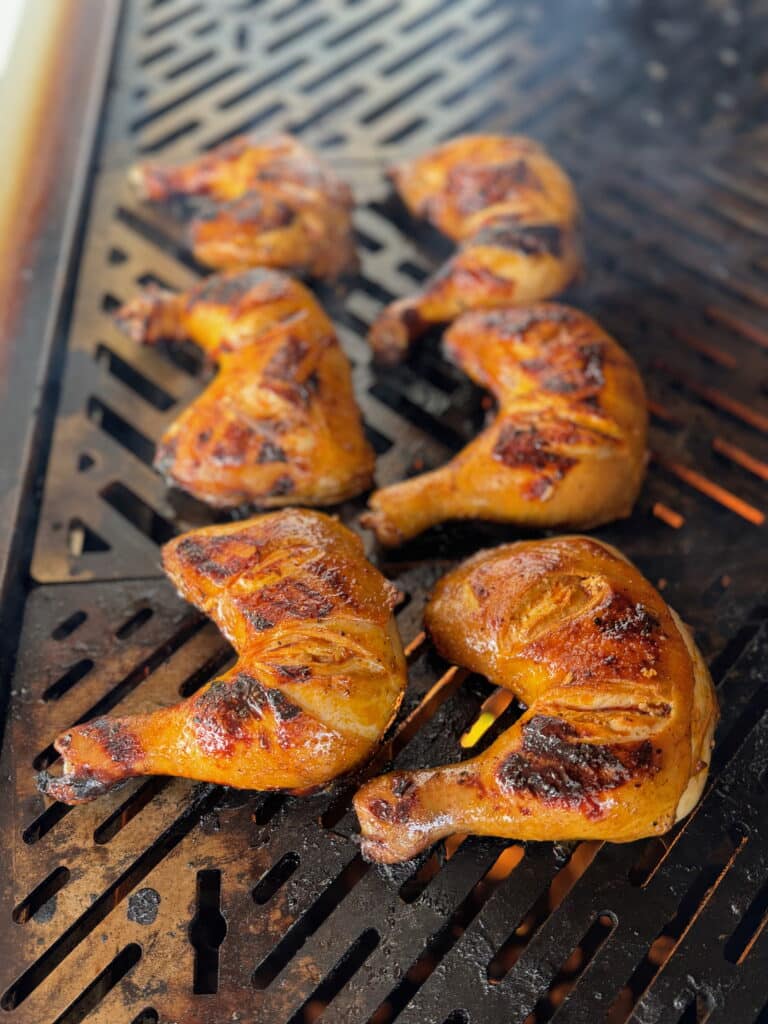 chicken inasal being grilled over fire on a grill grate