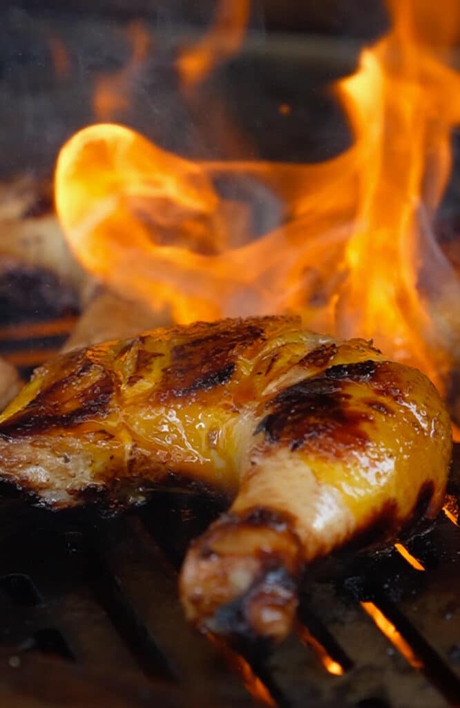 piece of chicken on a grill grate with flames