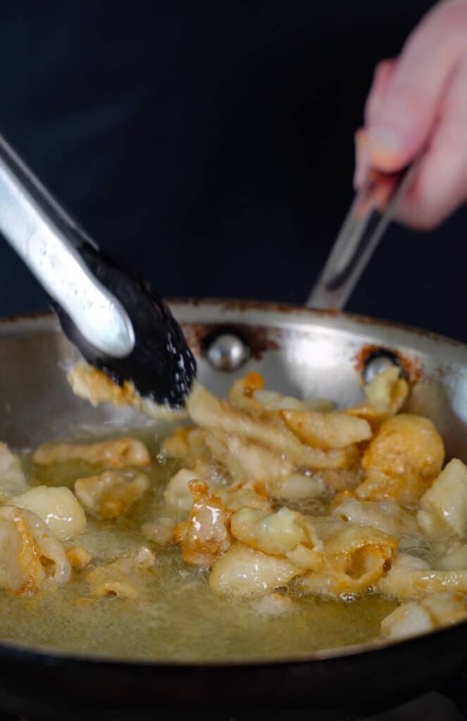 chicken skin being rendered down in a frying pan