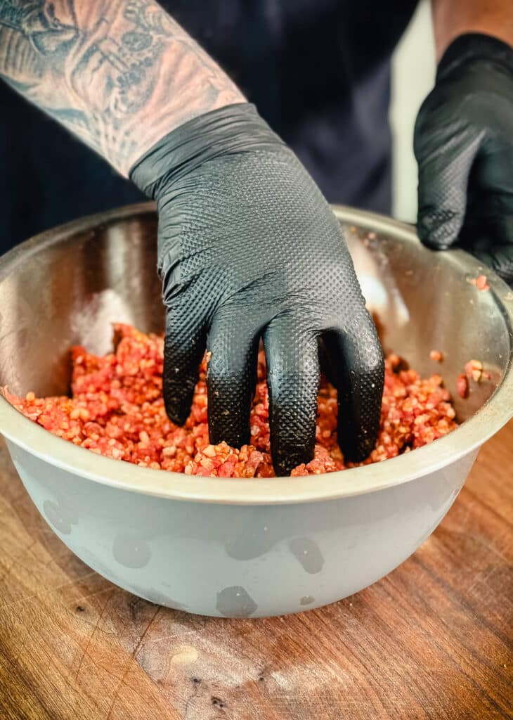 hand mixing bbq rub into ground pork in a bowl