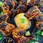 grilled chicken inasal on a black platter with rice and orange chicken oil