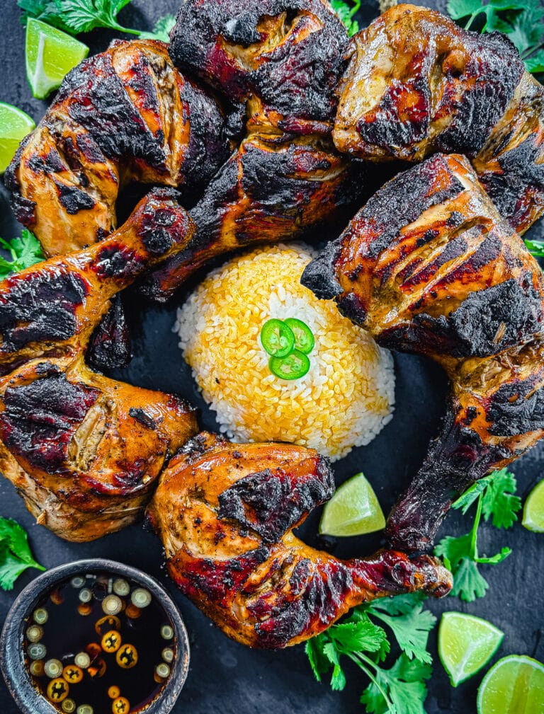 grilled chicken inasal on a black platter with rice and orange chicken oil