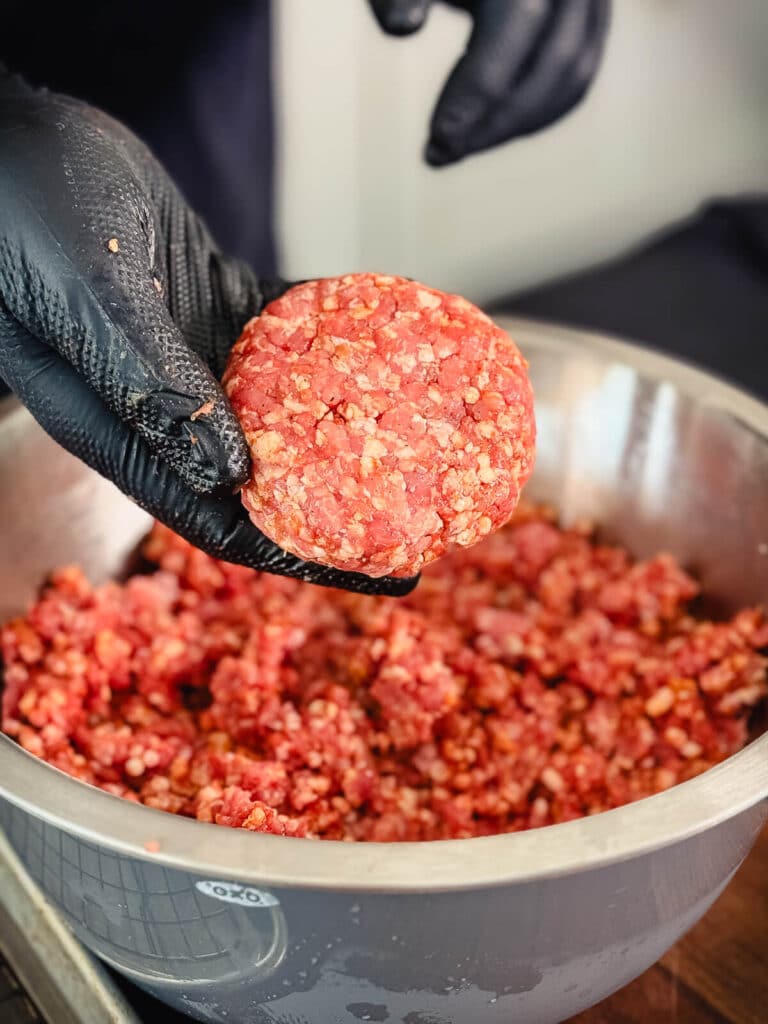 pork burger patty formed in gloved hand