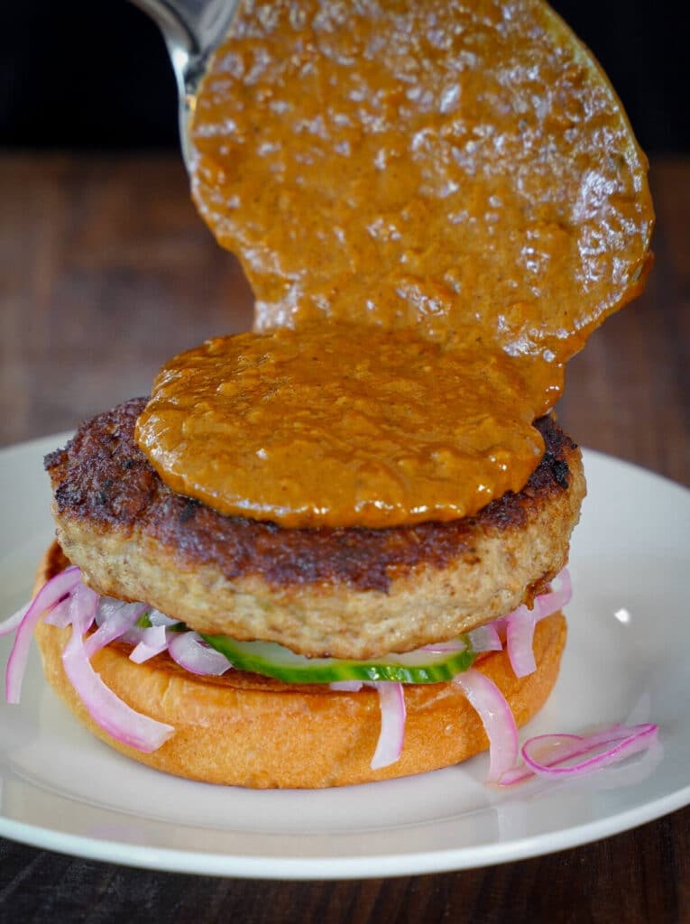 butter chicken sauce being added to a burger