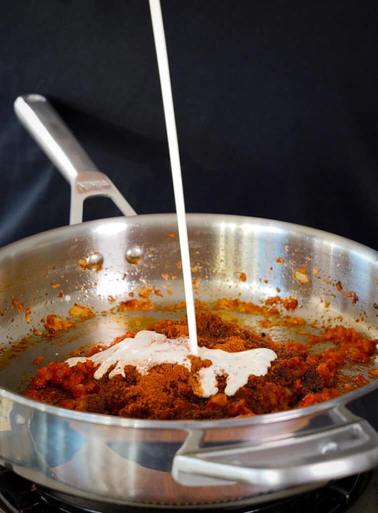 heavy cream being added to butter chicken sauce