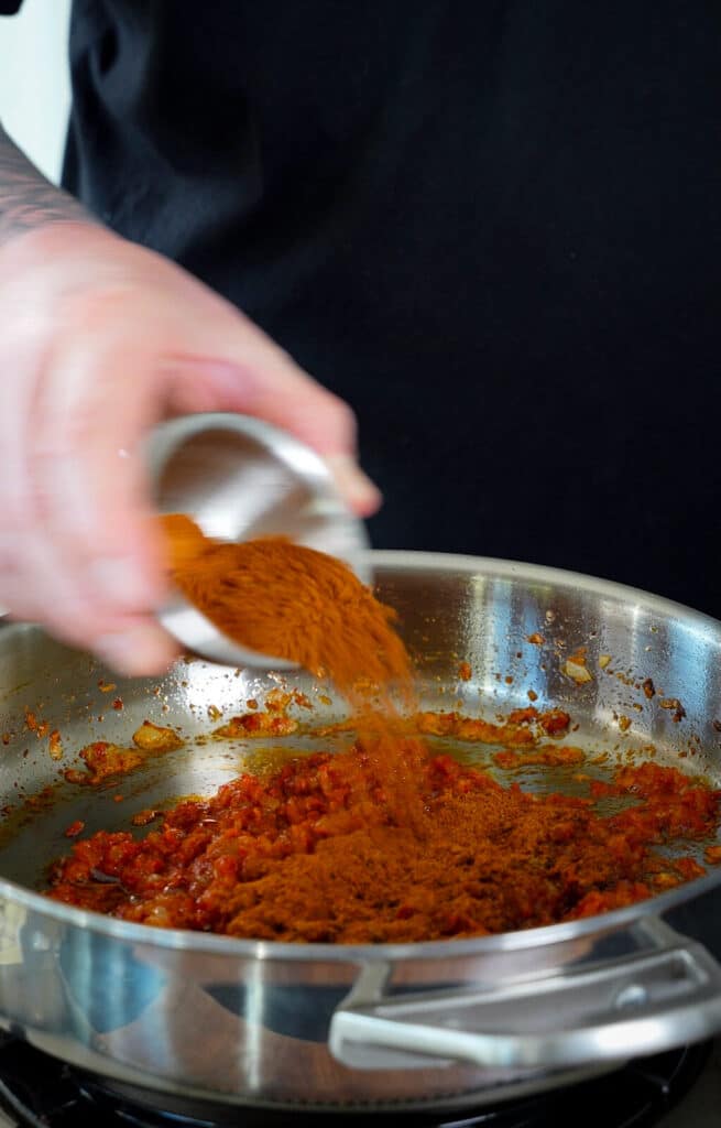 spices being added to butter chicken sauce