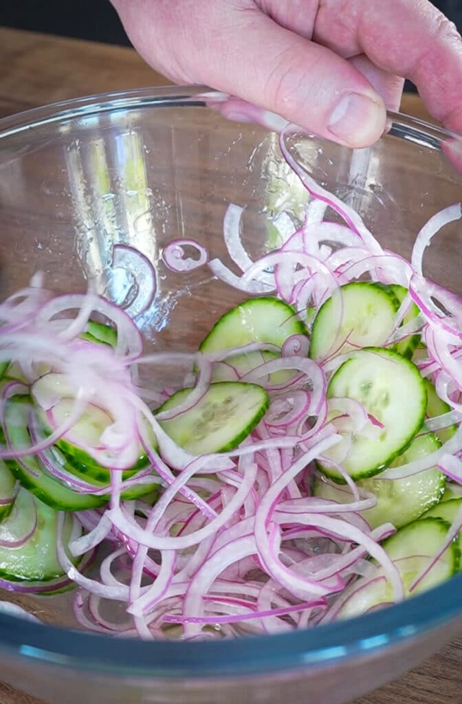 cucumber and red onion slaw in a glass bowl