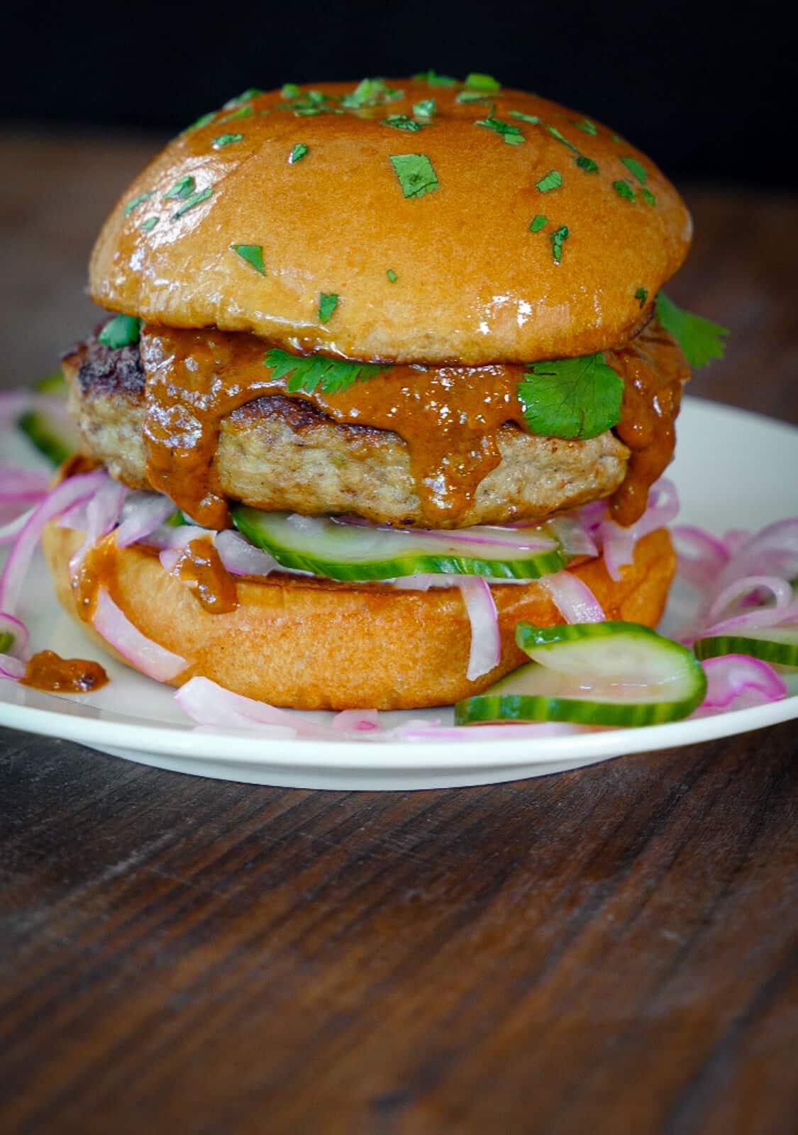 indian butter chicken burger sitting on a white plate