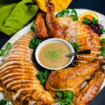 smoked turkey that's been sliced up and placed on a platter with a bowl of gravy