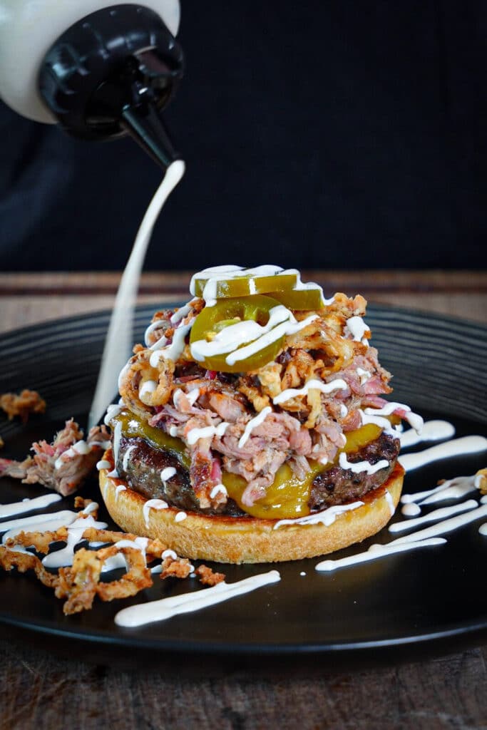 bbq ranch dressing being drizzled onto a ranch hand burger