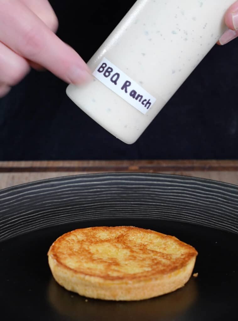 bottle of bbq ranch dressing near a toasted burger bun