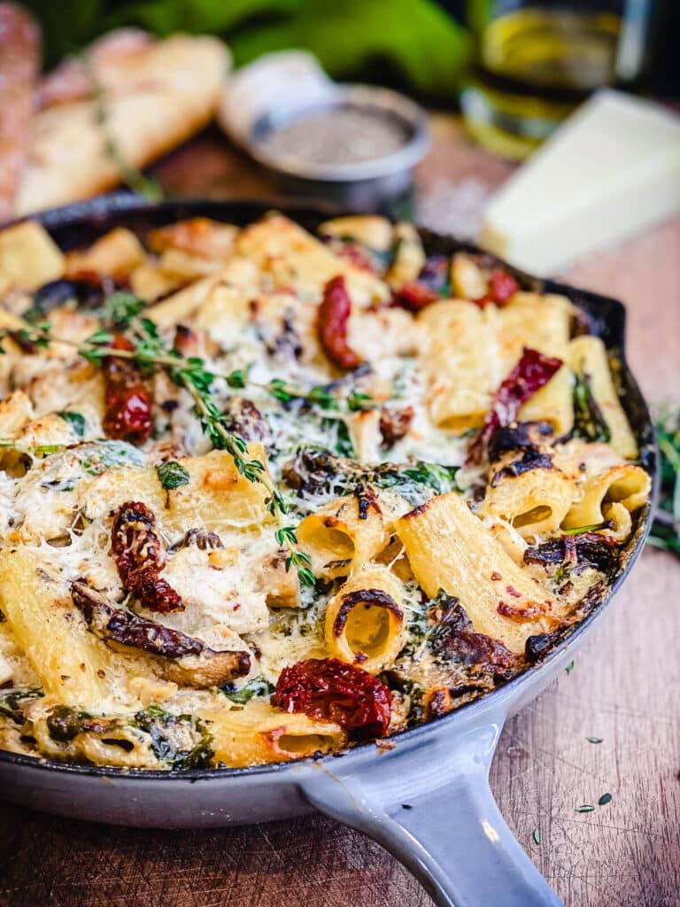 pan full of creamy chicken pasta on a wooden cutting board