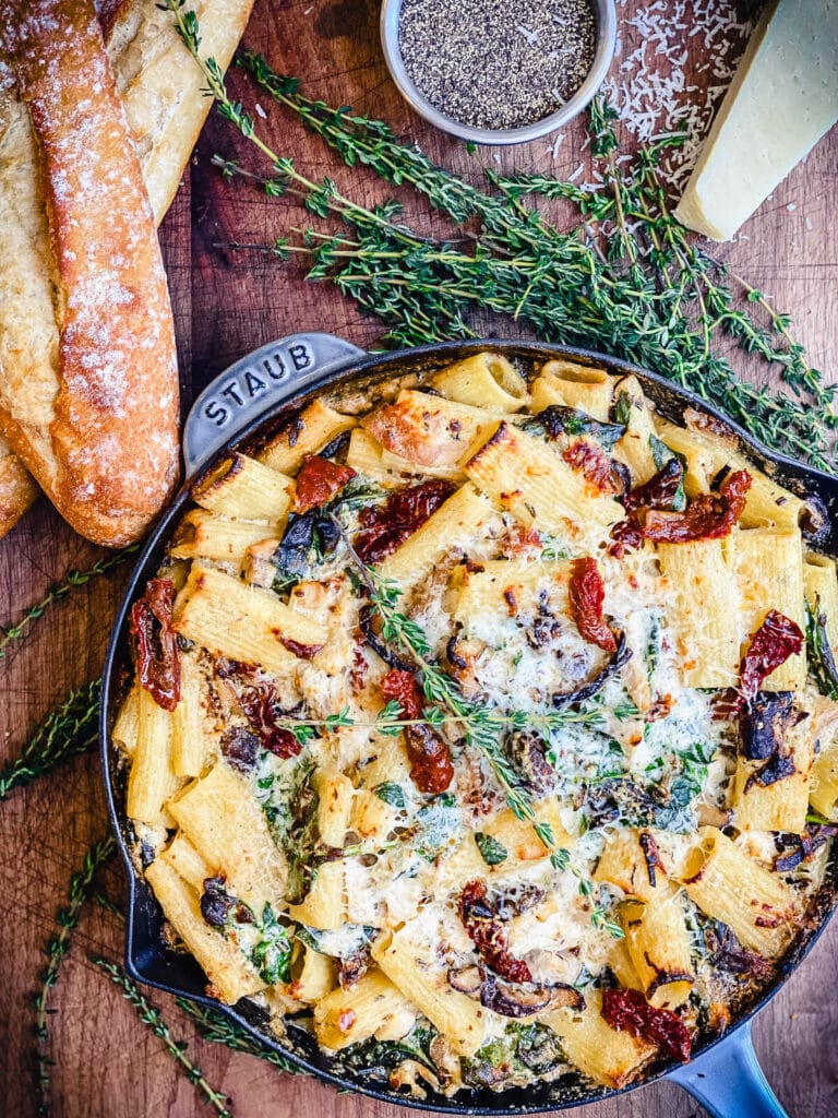 creamy chicken pasta bake in a grey skillet with bread and cheese