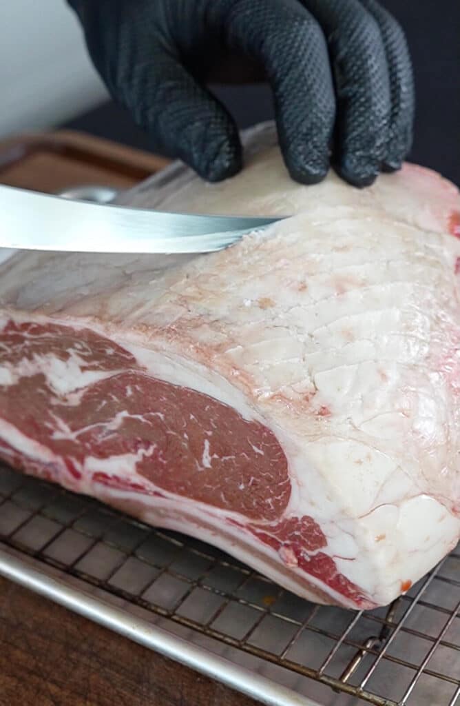 knife scoring the fat cap of a beef roast