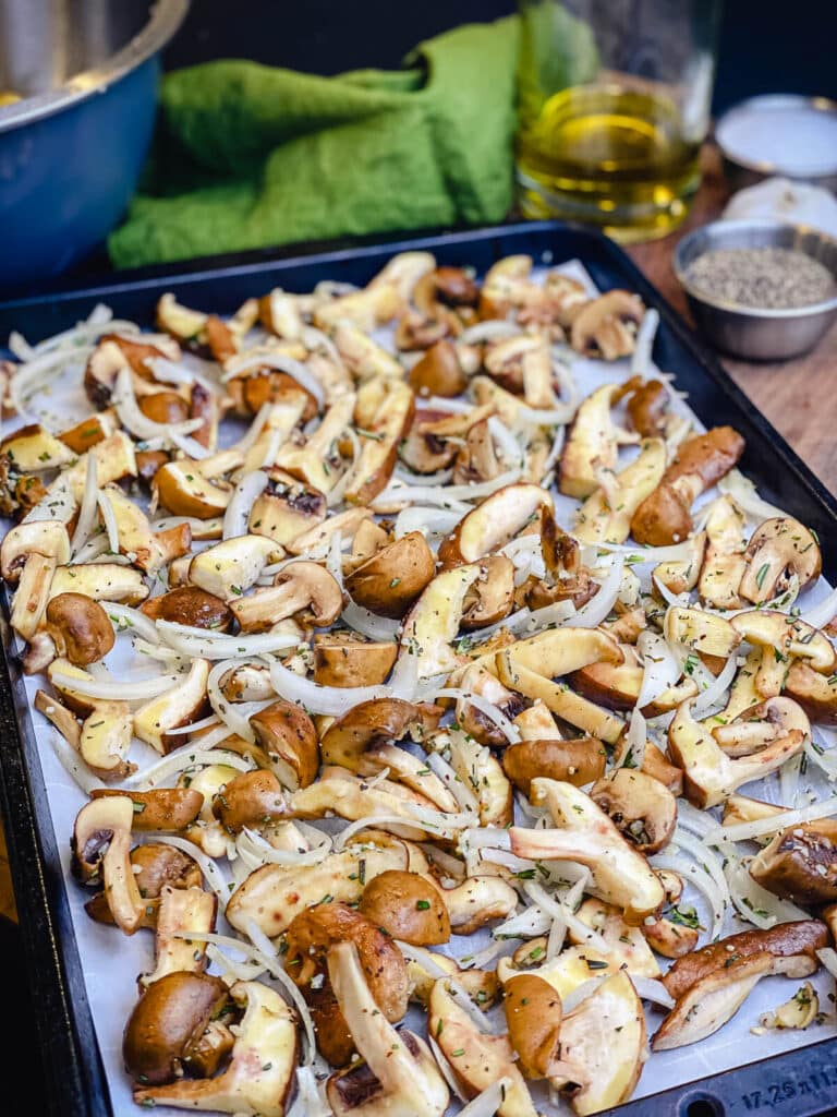 mushrooms and onions on a parchment lined baking sheet