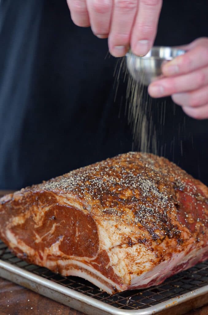 black pepper being added to a beef roast
