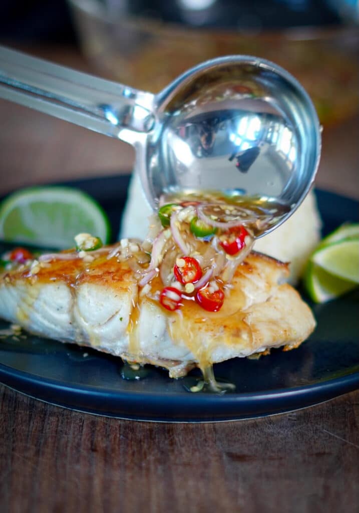 prik nam pla being poured over seared red snapper on a plate