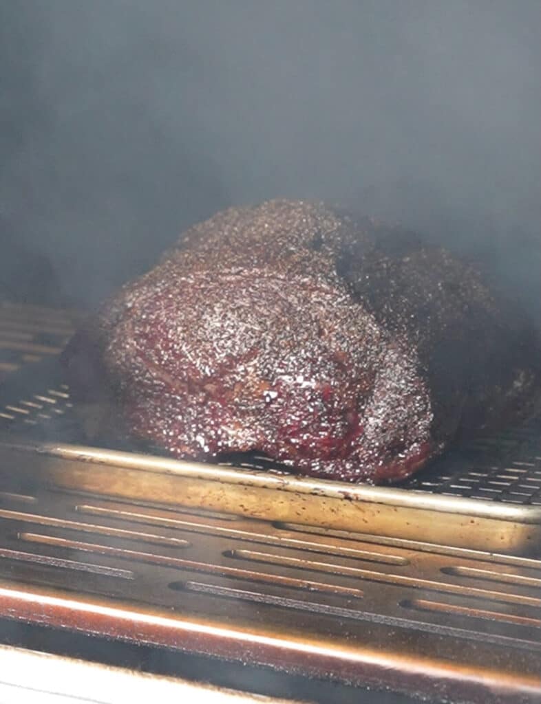 smoke surrounding a prime rib, inside of a pellet smoker