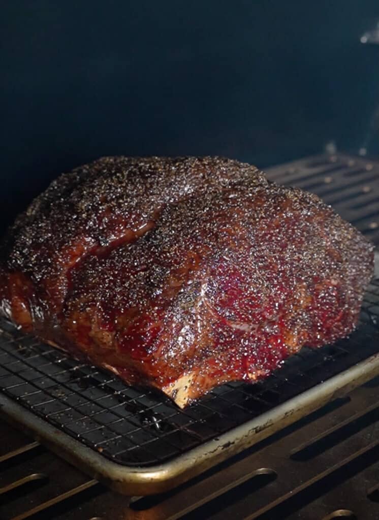 smoked prime rib in a smoker with bark built up