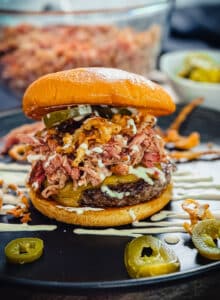 BBQ pulled pork burger on a black plate with jalepano