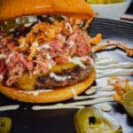 bbq pulled pork burger with jalapenos on a black plate