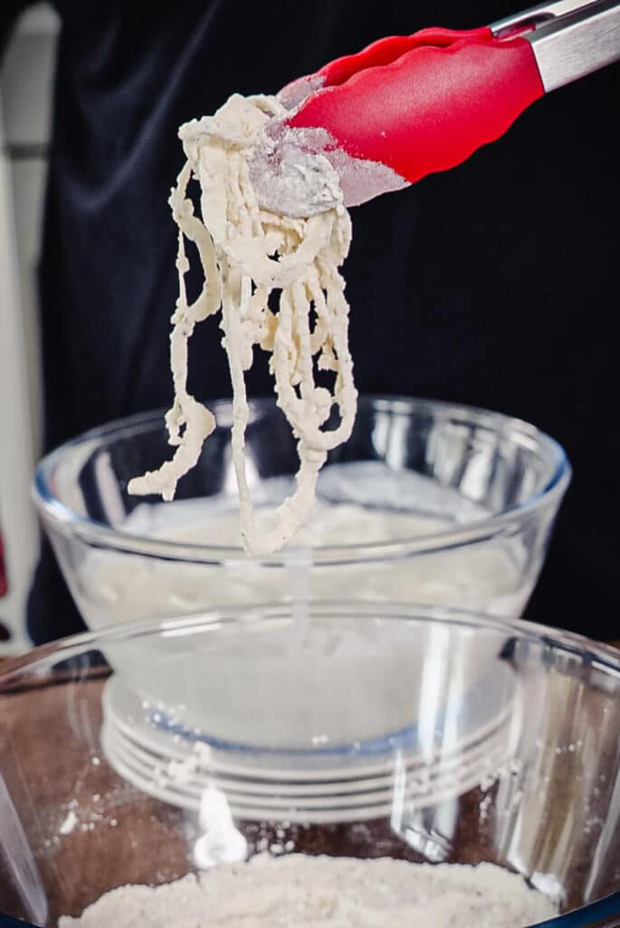 flour coated onions held by tongs